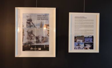 Na czarnej ścianie plakat promujący wystawę wernisażu, po prawej stronie opis wystawy
