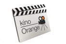 Na zdjęciu widnieje logo Kina Orange w formie klapsa filmowego. Obok napisu znajduje się rysunek kamery filmowej.