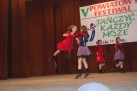 Zdjęcie przedstawia występ taneczny podczas V Powiatowego Festiwalu „Tańczyć Każdy Może”, który odbył się w Paczkowie w 2008 roku. Na scenie widoczne są cztery młode tancerki w strojach w kolorach czerwonym, czarnym i fioletowym. Dwie tancerki wykonują figurę akrobatyczną. 
