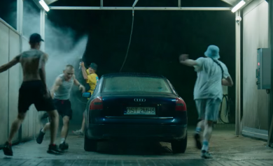 Scena z filmu odbywa się na myjni samochodowej. Czterech młodych mężczyzn bawiąc się, biega wokół samochodu, polewając się wodą.