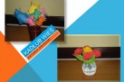Dwa zdjęcia rękodzieła (kwiaty w wazonach) wykonane metodą origami znajdujące się na niebiesko-biało-pomarańczowym tle z napisem ,,KADŁUB WIEŚ', ,,SZTUKA ORIGAMI'.