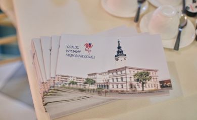 Na stole kilka sztuk Katalogu Wystawy Międzynarodowej, na pierwszej stronie ratusz Strzelec Opolskich 