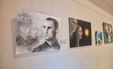 Obrazy wystawy 'Części Całości', od lewej obraz czarno biały przedstawiający 4 twarze, obraz przedstawiający 2 twarze na czarnym tle oraz żółta materia, następnie mniejszy obraz przedstawiający planetę Ziemie, która podziwiają ludzie z pewnej odległości, a po prawej stronie obraz przedstawiający serce ze skrzydłami dotykającymi planetę Ziemię na zielonym tle