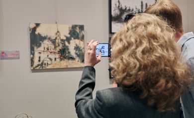 Kobieta fotografująca obraz wystawy 'Części Całości'