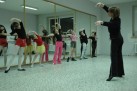Dziewczęta stojące tyłem do luster wykonują figurę, którą pokazuje im instruktorka. 